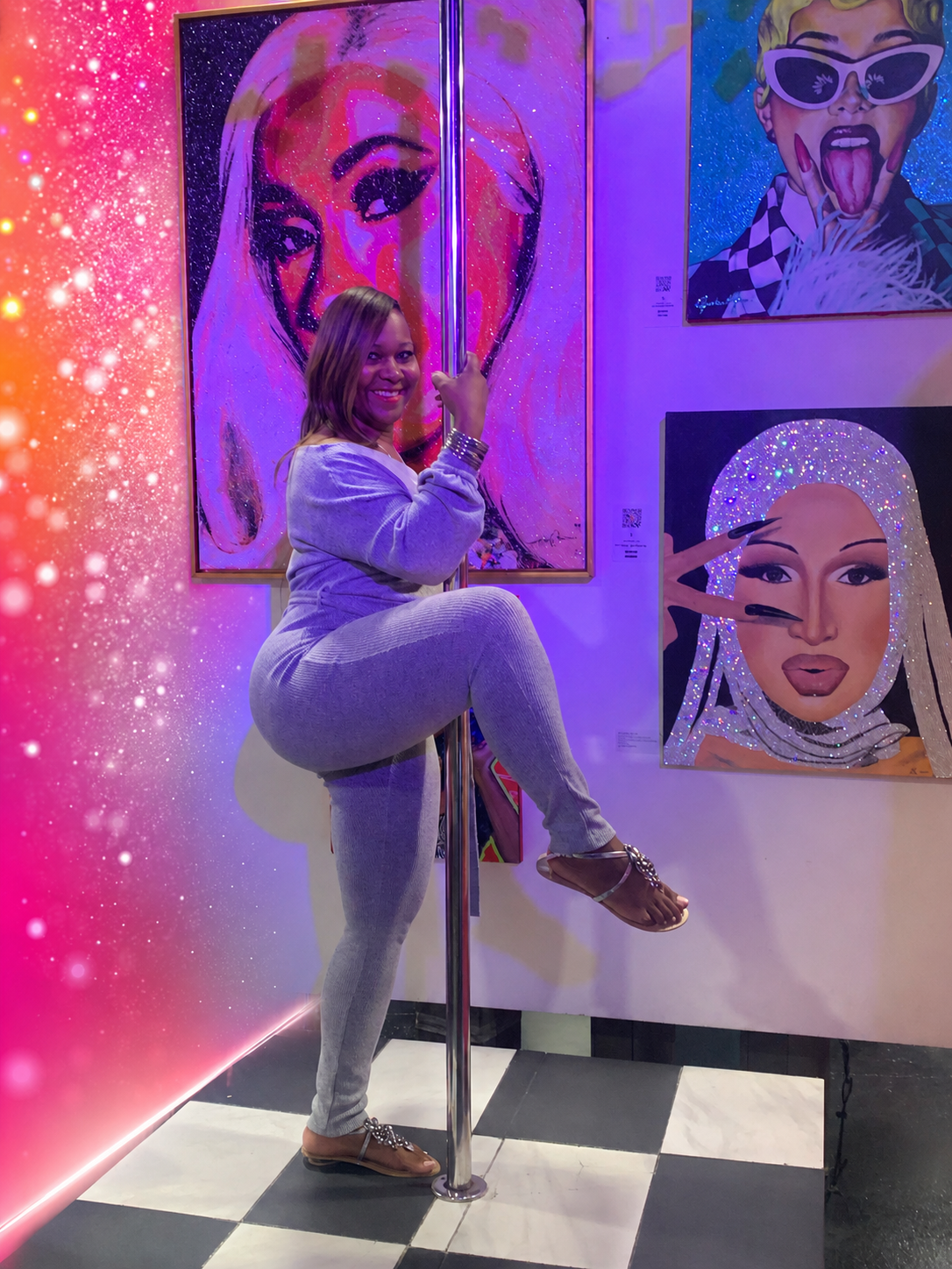 Sherrie Hazely posing playfully with a dance pole in a colorful art gallery